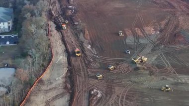 Buldozerler ve kazıcıların toprağı temizlediği, enkaz taşıyan kamyonların ve gelecekteki büyük depo yapılarının ana hatlarını belirleyen işaretli temellerin bulunduğu uçsuz bucaksız bir inşaat alanının havadan görüntüsü..