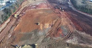 Buldozerler ve kazıcıların toprağı temizlediği, enkaz taşıyan kamyonların ve gelecekteki büyük depo yapılarının ana hatlarını belirleyen işaretli temellerin bulunduğu uçsuz bucaksız bir inşaat alanının havadan görüntüsü..