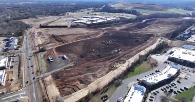 Buldozerler ve kazıcıların toprağı temizlediği, enkaz taşıyan kamyonların ve gelecekteki büyük depo yapılarının ana hatlarını belirleyen işaretli temellerin bulunduğu uçsuz bucaksız bir inşaat alanının havadan görüntüsü..