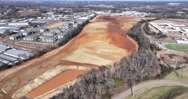 Buldozerler ve kazıcıların toprağı temizlediği, enkaz taşıyan kamyonların ve gelecekteki büyük depo yapılarının ana hatlarını belirleyen işaretli temellerin bulunduğu uçsuz bucaksız bir inşaat alanının havadan görüntüsü..