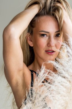 Güzel bir Doğu Avrupalı iç çamaşırı modeli beyaz bir yatakta, doğal pencere ışığıyla hafifçe aydınlatılarak samimi, sakin ve sıcak bir ev atmosferi yaratıyor..