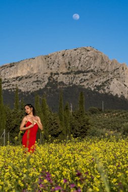 Çarpıcı bir Avrupalı model, İspanyol kır çiçeklerinin arasında yaz sonlarındaki parlaklığın tadını çıkarıyor. Doğanın güzelliğini zarafetle somutlaştırıyor..