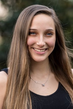 Genç ve güzel bir kadın bahar havasında zarif bir şekilde parkta yürüyor. Etrafı çiçeklerle ve yumuşak günışığıyla çevrili, günün sakin ve huzurlu ritminin tadını çıkarıyor..