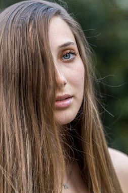 Genç ve güzel bir kadın bahar havasında zarif bir şekilde parkta yürüyor. Etrafı çiçeklerle ve yumuşak günışığıyla çevrili, günün sakin ve huzurlu ritminin tadını çıkarıyor..