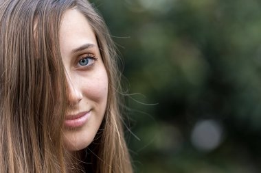 Genç ve güzel bir kadın bahar havasında zarif bir şekilde parkta yürüyor. Etrafı çiçeklerle ve yumuşak günışığıyla çevrili, günün sakin ve huzurlu ritminin tadını çıkarıyor..