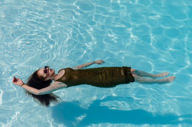 Muhteşem bir esmer bikini modeli Karayipler 'de bir havuz kenarında güneşleniyor ve nazik Tradewind' leri emiyor. Altın tenini mükemmelleştirirken sıcaklığın, huzurun ve tropikal titreşimlerin tadını çıkarıyor..