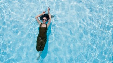 Muhteşem bir esmer bikini modeli Karayipler 'de bir havuz kenarında güneşleniyor ve nazik Tradewind' leri emiyor. Altın tenini mükemmelleştirirken sıcaklığın, huzurun ve tropikal titreşimlerin tadını çıkarıyor..