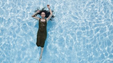 Muhteşem bir esmer bikini modeli Karayipler 'de bir havuz kenarında güneşleniyor ve nazik Tradewind' leri emiyor. Altın tenini mükemmelleştirirken sıcaklığın, huzurun ve tropikal titreşimlerin tadını çıkarıyor..