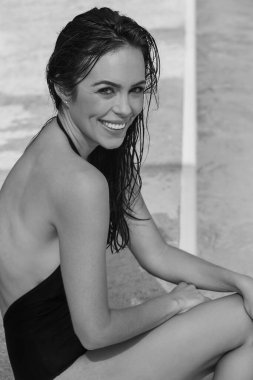 Göz kamaştırıcı bir esmer bikini modeli özel bir havuzda dinleniyor. Güneş ışığı suyun üzerinde parıldıyor. Huzurlu bir zarafet, huzurlu bir lüks ve huzur dolu vahada tasasız bir rahatlama sağlıyor..