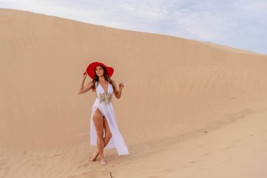 Zarif model kum tepelerindeki doğanın güzelliğini kucaklıyor, engin, doğal ihtişamın arkaplanına karşı zarafeti simgeliyor.