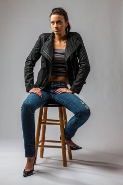 Genç esmer bir manken kameraya kendine güvenen bir poz veriyor. Temiz bir stüdyo ortamında, beyaz bir arka planla çerçevelenmiş, tarzını, duruşunu ve modern zarafetini ön plana çıkarıyor..