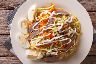 Beef heart with vegetables and eggs close-up on a plate horizont