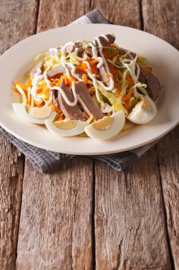 Salad from beef heart with eggs and vegetables close-up. Vertica