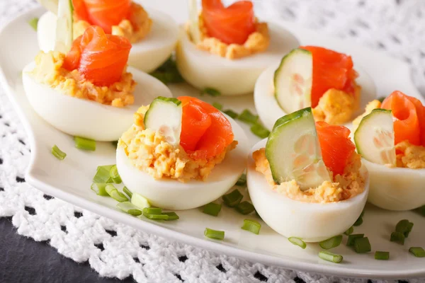 Ägg fyllda med lax och gurka närbild på en tallrik. — Stockfoto