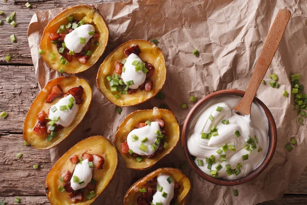 Peles de batata com queijo, bacon e nata azeda close-up. horizonte — Fotografia de Stock