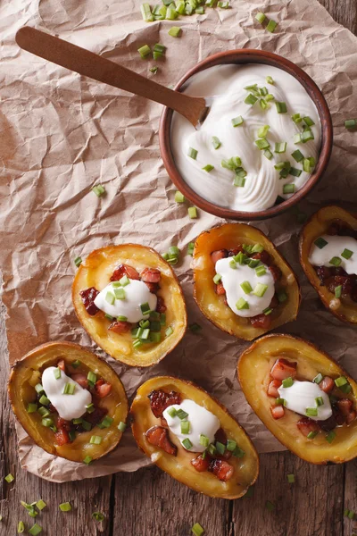 Peles de batata com queijo, bacon e nata azeda close-up. Vertica — Fotografia de Stock