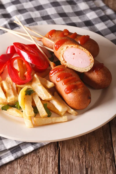 Corn dog, french fries and vegetables on a plate close-up. Verti — Stock Photo, Image