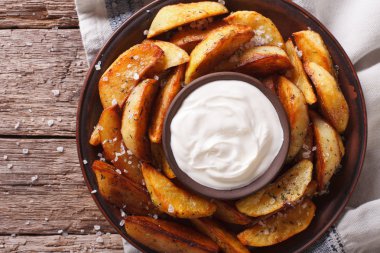 Baharatlı patates dilimleri ile bir tabak portre üzerinde otlar. Yatay için