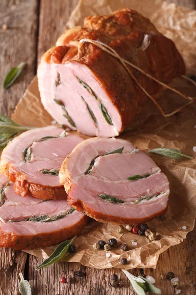 Roll pork stuffed with sage close up on the table. Vertical — Stock Photo, Image