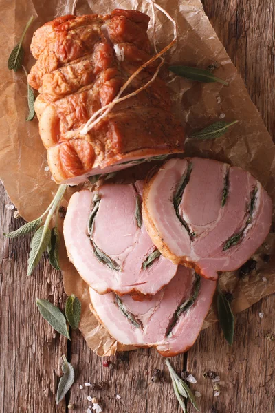 Baked Roll of pork stuffed with sage close up on the table. vert — Stock Photo, Image