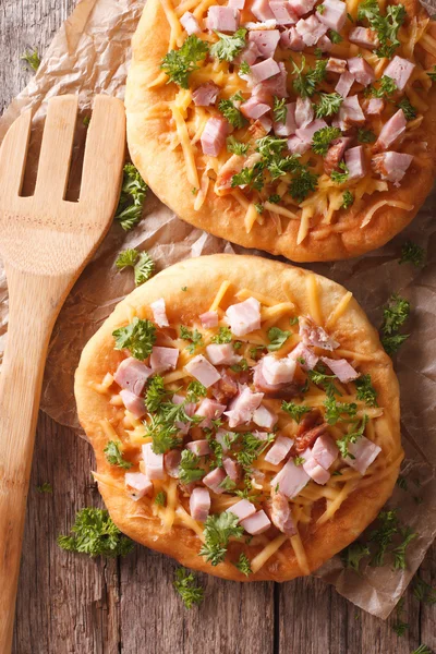 Hungarian pancakes langos with ham and cheese on the table. Vert