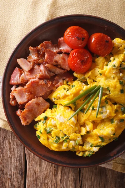 Scrambled eggs with chives, bacon and tomatoes close-up. Vertica — Stock Photo, Image