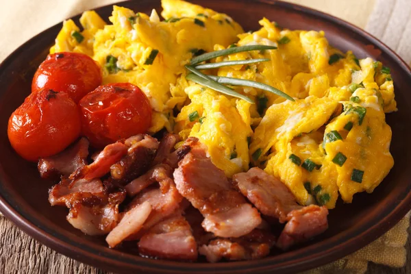 Scrambled eggs with chives, bacon and tomatoes close-up. horizon — Stock Photo, Image