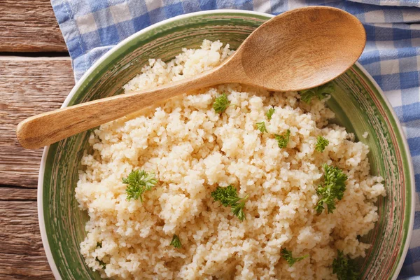 Nützlicher Bulgur mit Petersilie in Großaufnahme auf einem Teller auf dem Tisch. hor — Stockfoto