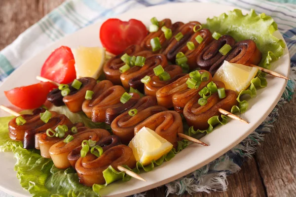 Anneaux de calamar sur des brochettes avec du citron et des légumes en gros plan. hor — Photo