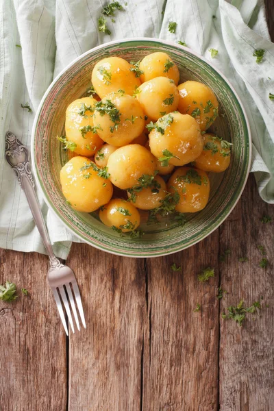 Geglazuurde nieuwe aardappelen met peterselie close-up op tafel. verticale — Stockfoto