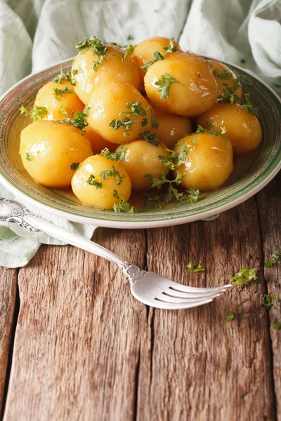 Gekarameliseerde nieuwe aardappelen met peterselie close-up op tafel. Ver — Stockfoto