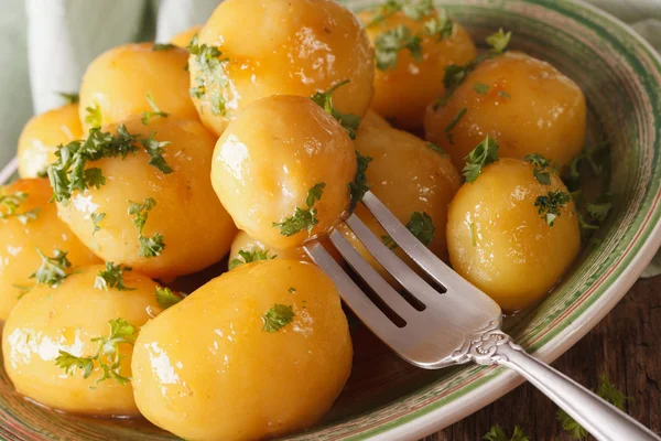 Patatas nuevas caramelizadas con hierbas de cerca en un plato. Horizonte —  Fotos de Stock