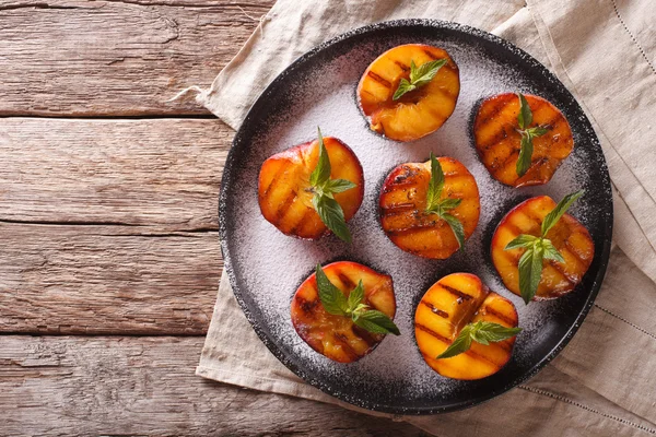 Reife Pfirsiche mit Puderzucker und Minze auf einem Teller gegrillt. ho — Stockfoto