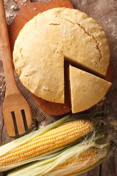 Round loaf of corn bread close-up on a wooden board. Vertical to — Stock Photo, Image