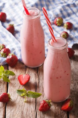 Cam şişelerde taze yapılmış çilekli smoothie yakın çekim. Vert