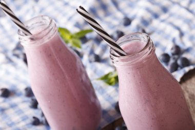 Bir cam şişe yakın çekim yaban mersini smoothies yenileniyor. Yatay