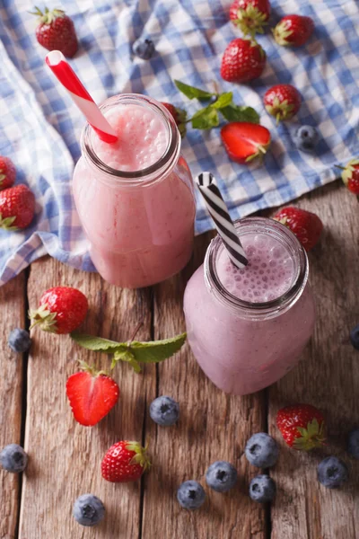 Milkshakes met aardbeien en blauwe bessen in flessen close-up — Stockfoto