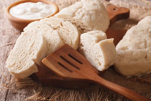 Fresh sliced yeast knedliks and sour cream close-up. horizontal — Stock Photo, Image