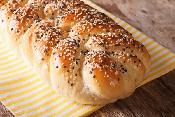 Tasty braided bun with sesame seeds closeup. horizontal — Stock Photo, Image