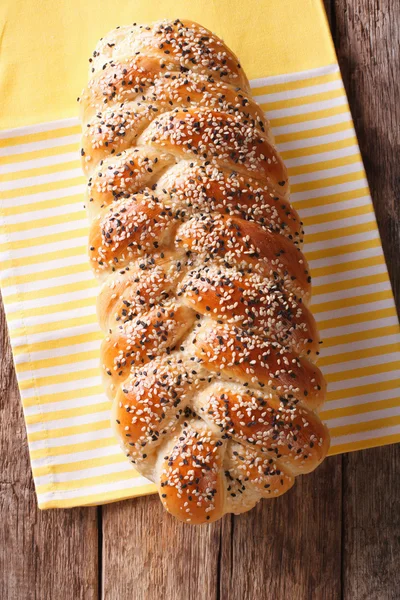 Freshly baked loaf of braided, with sesame seeds close up. Verti — Stock Photo, Image