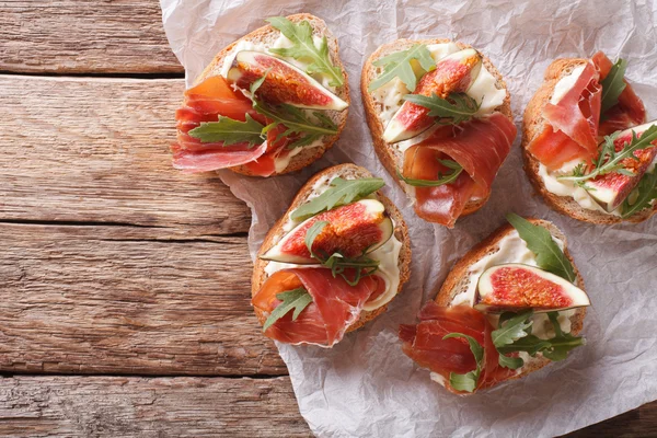 Bruschetta with figs, prosciutto, arugula and cream cheese close — Stock Photo, Image