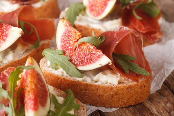 Bruschetta with figs, prosciutto, arugula and cream cheese macro — Stock Photo, Image