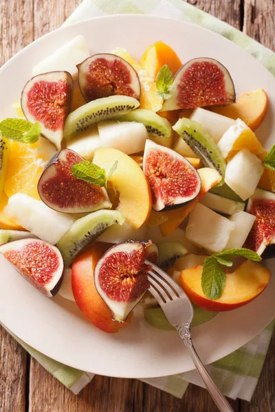 Fruit salad with fig, peach, melon, kiwi and orange close-up on — Stock Photo, Image