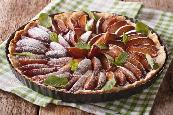 Plum cake with mint and powdered sugar in baking dish close up. — Stock Photo, Image