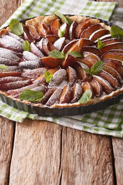 Sweet plum tart with mint and powdered sugar close-up. vertical — Stock Photo, Image