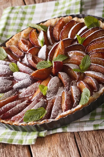 Freshly baked plum tart decorated with mint close-up. Vertical — Stock Photo, Image