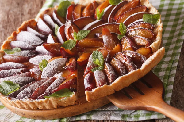 Freshly baked sliced tart of ripe plums close-up. horizontal