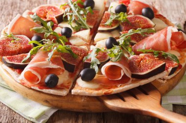 İncir, jambon, peynir ve arugula yakın çekim ile dilimlenmiş pizza. horizo