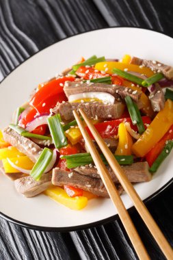 Biberden Asya salatası, sığır dili, soğan ve susam tohumları masanın üstünde yakın plan. dikey