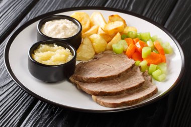 Boiled veal or Tafelspitz is the king of the beef dishes in Vienna close-up in a plate on the table. horizonta